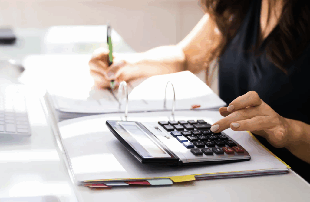 Personne effectuant des calculs budgétaires sur une calculatrice et des documents comptables. Norme 18 - M57